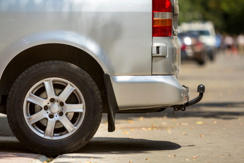 Close-up side view detail of silver passenger medium size luxury minibus van with tow-bar parked on